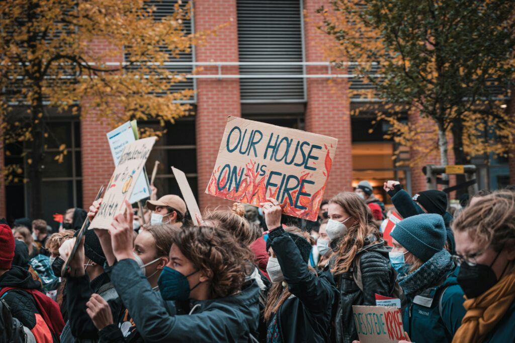Eine Klimademo, im Fokus ein Demoschild mit der Aufschrift: Our House is on Fire.